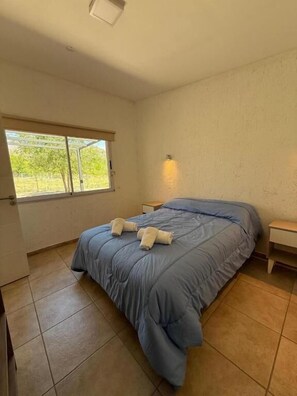 A bedroom with a bed, a window, and a nightstand.