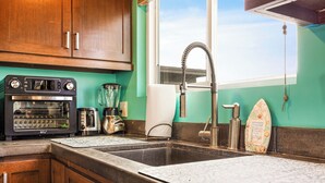 Una cocina con horno integrado, cafetera, licuadora y grifo de acero inoxidable.
