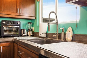 A kitchen with a built-in oven, a coffee maker, a blender, and a stainless steel faucet. - 1 Block to Beach | Charming 2BR Newport Bungalow w/ Patios, Bikes & Gear (Newport Beach)