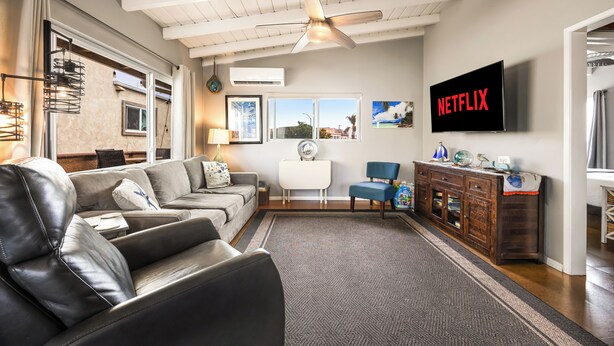 Una sala de estar moderna con un sofá de cuero, un televisor y un ventilador de techo.