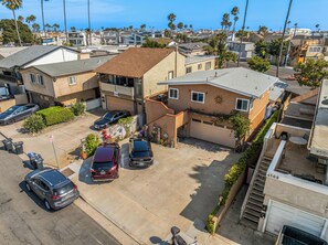 A residential area with multiple houses, a parking lot, and a clear view of the ocean. - 1 Block to Beach | Charming 2BR Newport Bungalow w/ Patios, Bikes & Gear (Newport Beach)