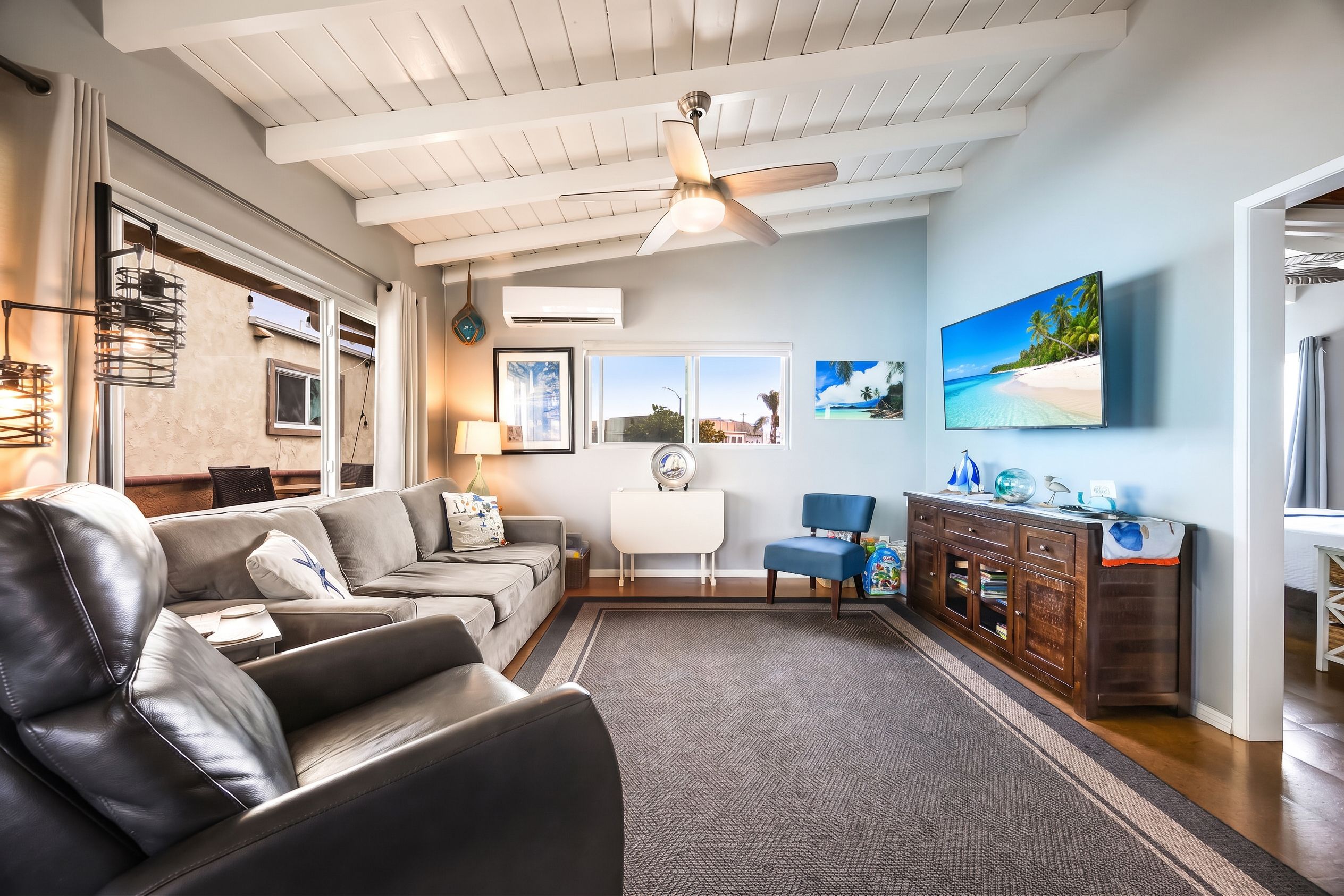 A living room with a leather sofa, a coffee table, a TV, and a ceiling fan.