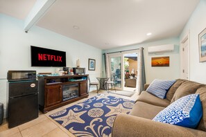 A living room with a flat-screen TV displaying 'NETFLIX,' a kitchen area with a coffee machine, and a patterned rug. - 1 Block to Beach | Newport Beach Studio w/ Modern Bath, Courtyard & Bikes (Newport Beach)