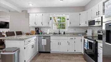 Cocina moderna con armarios blancos, electrodomésticos de acero inoxidable y encimera de granito.