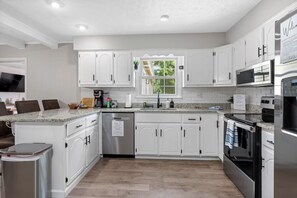 A modern kitchen with white cabinetry, stainless steel appliances, and a granite countertop.