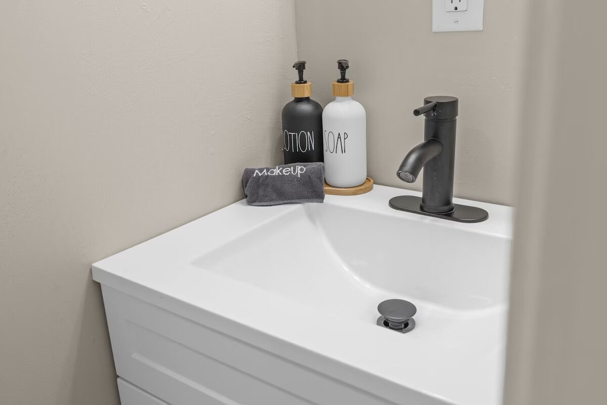 A bathroom sink with a modern faucet, a towel, and two soap bottles.