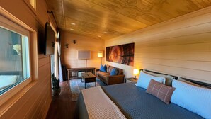 Una camera accogliente con un letto, un divano, un piccolo tavolo e una TV a muro.