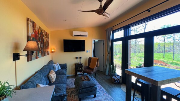 Ein Wohnzimmer mit einer Couch, Hocker, Tisch und Deckenventilator.