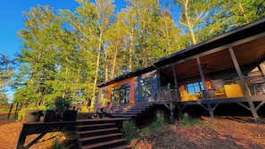 A modern cabin with a wooden exterior, a covered porch, and a staircase leading to the entrance. - Bison Farm - Vista Cabin (2 BR option) (Culpeper)