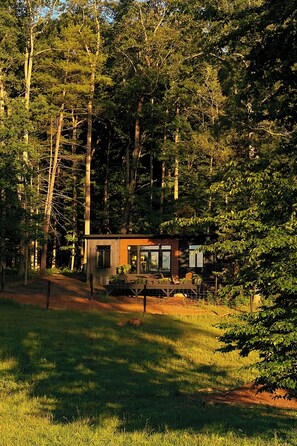 A cabin surrounded by trees with a deck and outdoor seating. - Bison Farm - Vista Cabin (2 BR option) (Culpeper)