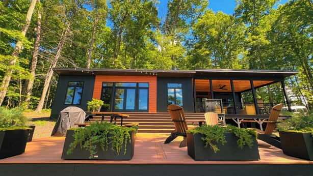 Una baita moderna con una veranda, posti a sedere all'aperto e una zona riparata con ventilatore a soffitto.