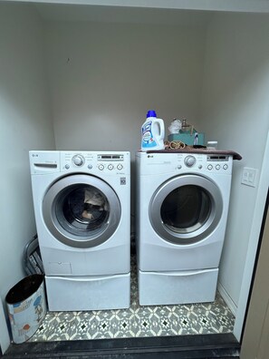 Two white LG Direct Drive front-loading washing machines in a laundry room with patterned floor tiles. - Cozy cottage close to USC, downtown and quick trip to Culver City and Hollywood. (Los Angeles)