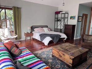 A bedroom with a bed, a chair, a dresser, a chest of drawers, and a hanging light fixture. - Cozy cottage close to USC, downtown and quick trip to Culver City and Hollywood. (Los Angeles)