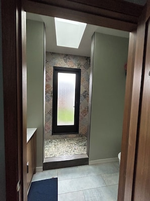 A narrow hallway with a skylight, a patterned wall, and a door leading to a room with a tiled floor. - Cozy cottage close to USC, downtown and quick trip to Culver City and Hollywood. (Los Angeles)