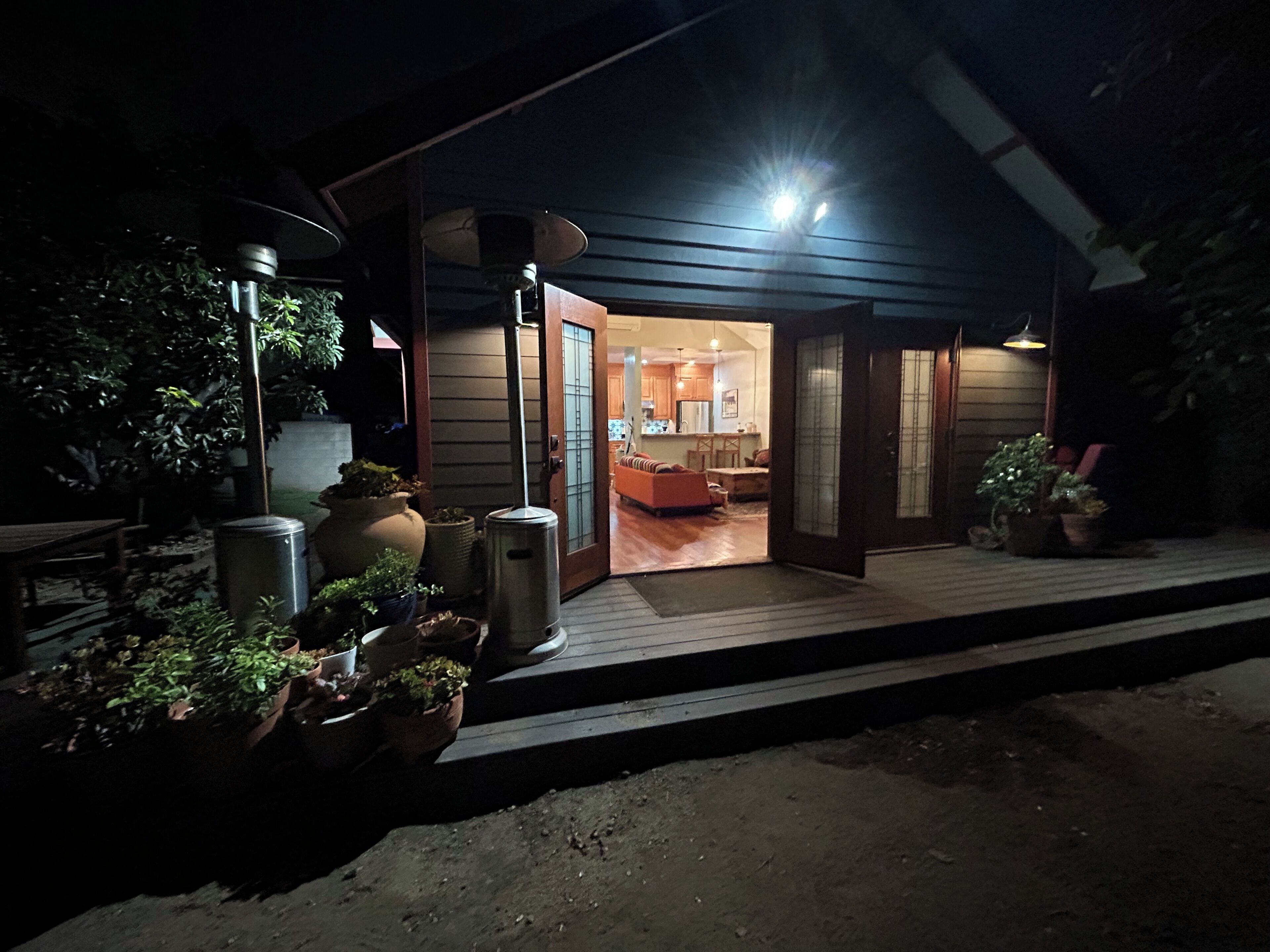A modern house with a wooden deck, a dining area, and a kitchen visible through an open door.