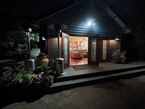 A modern house with a wooden deck, a dining area, and a kitchen visible through an open door. - Cozy cottage close to USC, downtown and quick trip to Culver City and Hollywood. (Los Angeles)