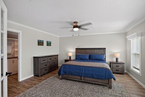 A bedroom with a bed, bedside tables, a ceiling fan, and a window with blinds.