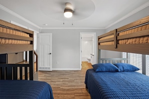 A bedroom with bunk beds, a door, a staircase, and a window.