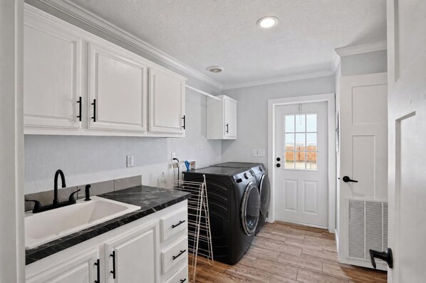 A compact kitchen with white cabinets, a black countertop, and a built-in washing machine.