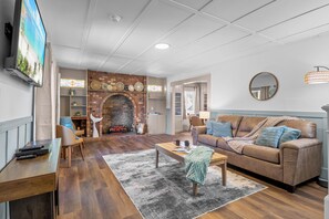Ein Wohnzimmer mit Kamin, Fernseher, Sofa und Couchtisch.