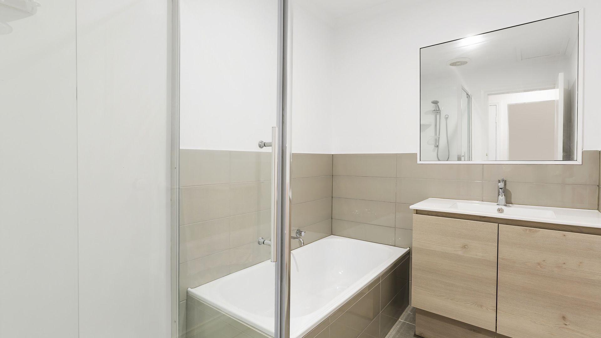 Ein modernes Badezimmer mit einer Duschkabine aus Glas, einer weißen Badewanne und einem Holzbadezimmer mit Spiegel.