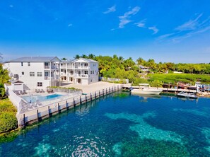 A multi-story hotel with a swimming pool and docked boats.