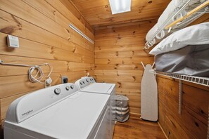 A compact, wooden-paneled room with a Whirlpool washer and dryer, a small trash bin, and a shelf with a white towel. - Spacious Mountain Getaway Minutes from Boone (Boone)