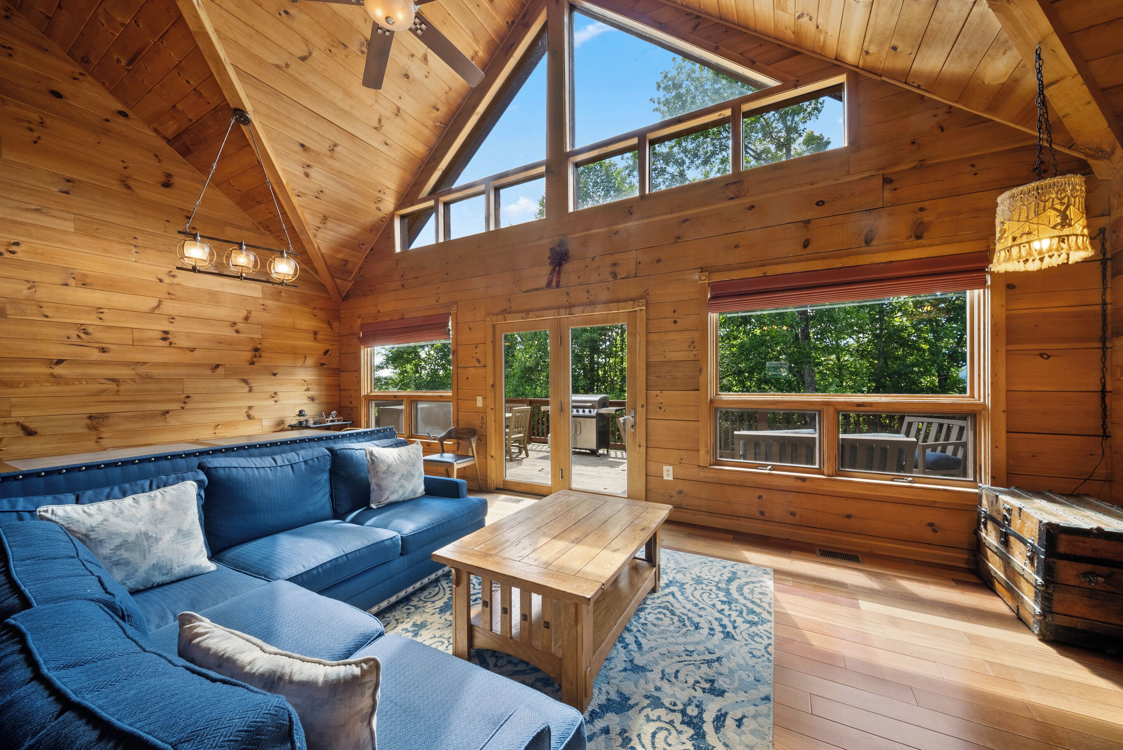 L'intérieur d'un chalet en bois, avec un canapé, une table et de grandes fenêtres.