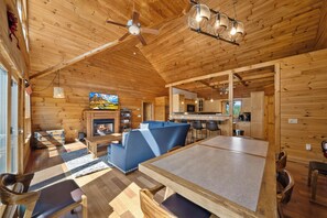 L’intérieur d’un chalet confortable, avec une cheminée, un coin repas et une cuisine.