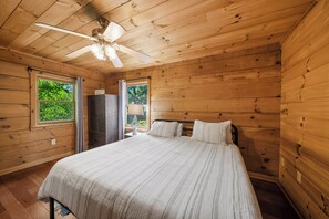 A wooden cabin bedroom with a bed, a ceiling fan, and two windows. - Spacious Mountain Getaway Minutes from Boone (Boone)