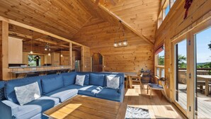 A wooden interior with a sectional sofa, a wooden table, and a view through a glass door. - Spacious Mountain Getaway Minutes from Boone (Boone)