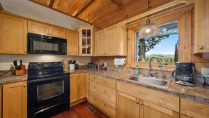A kitchen with wooden cabinets, a black microwave, a stove, a sink, and a coffee maker. - Spacious Mountain Getaway Minutes from Boone (Boone)