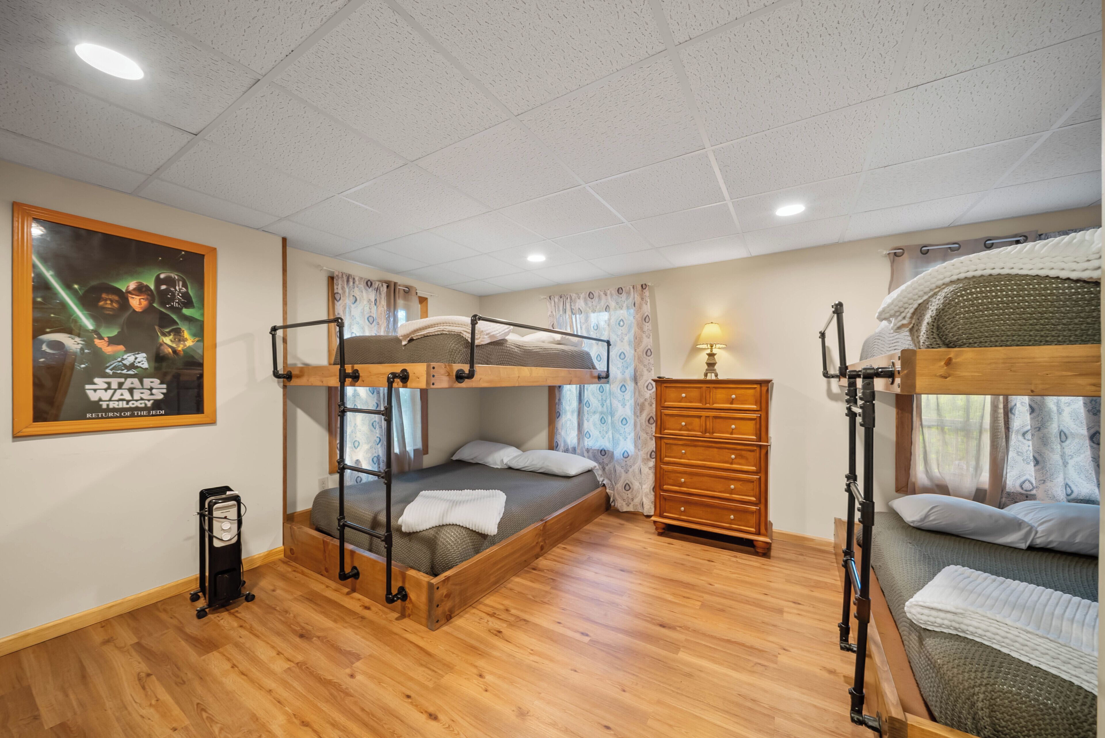 A bunk bed room with a Star Wars themed poster, wooden furniture, and a dresser.