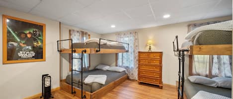 Une chambre avec un lit superposé, une affiche sur le thème de Star Wars, des meubles en bois et une commode.