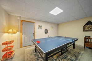 A room with a ping pong table, a dartboard, and a wall-mounted shelf with decorative items. - Mountain Retreat with Long-Range Views Near Boone (Boone)