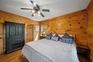 A bedroom with a bed, wooden walls, a ceiling fan, and a dresser. - Mountain Retreat with Long-Range Views Near Boone (Boone)