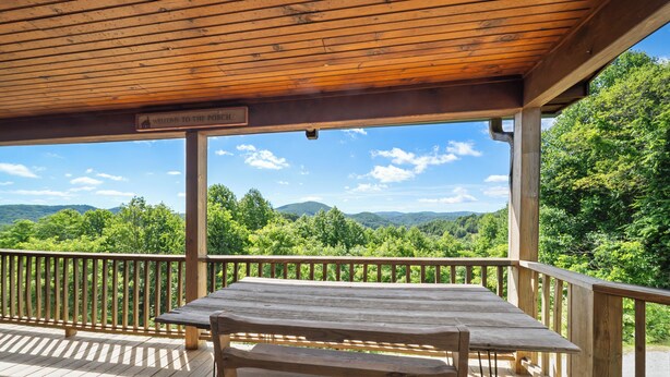 A wooden deck with a table and bench, overlooking a forested landscape with hills. - Mountain Retreat with Long-Range Views Near Boone (Boone)