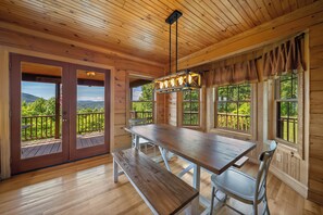 A wooden interior with a large table and bench, large windows with views of greenery, and a ceiling with wooden beams. - Mountain Retreat with Long-Range Views Near Boone (Boone)