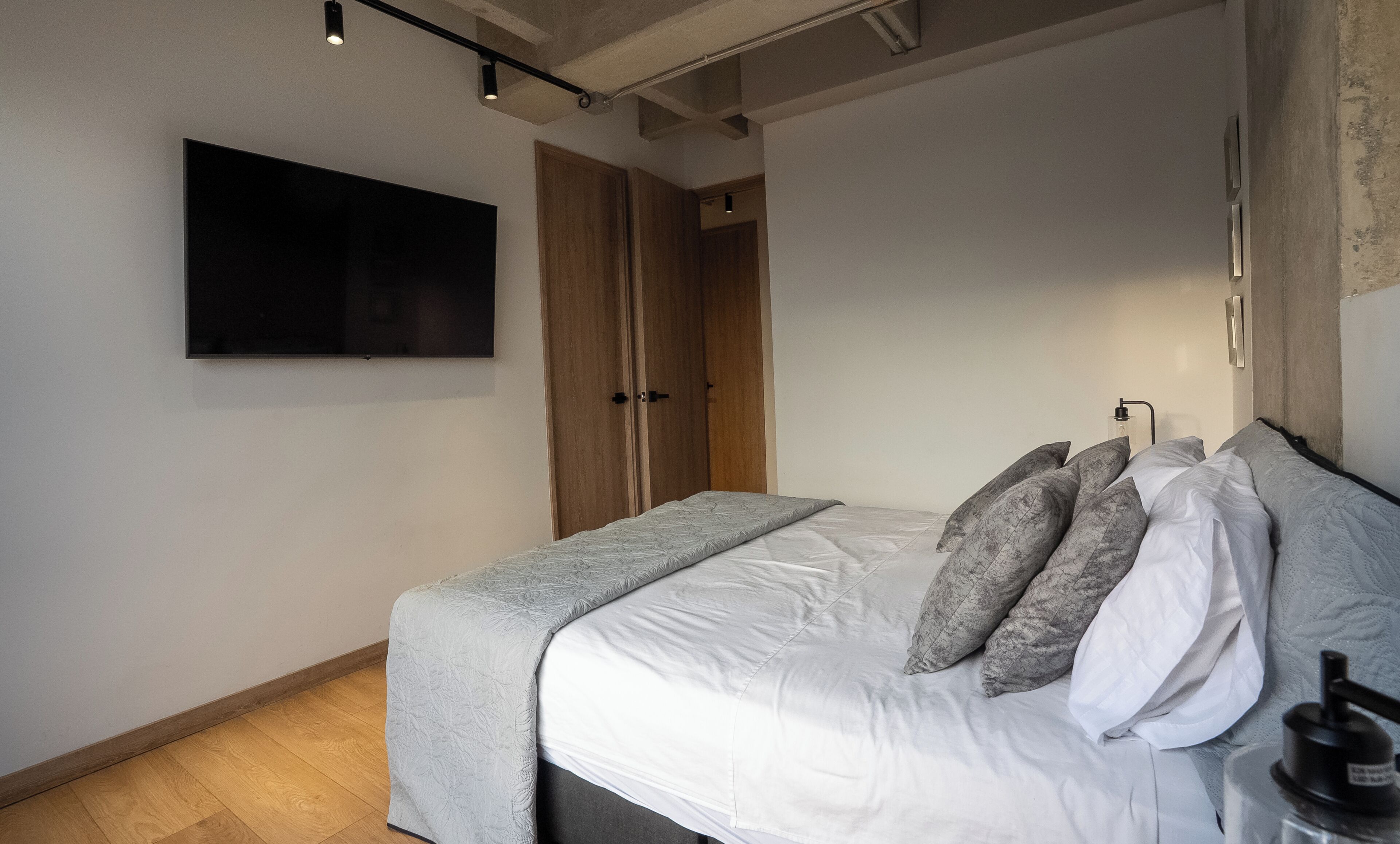 Un dormitorio con cama, almohadas, un televisor y un armario.