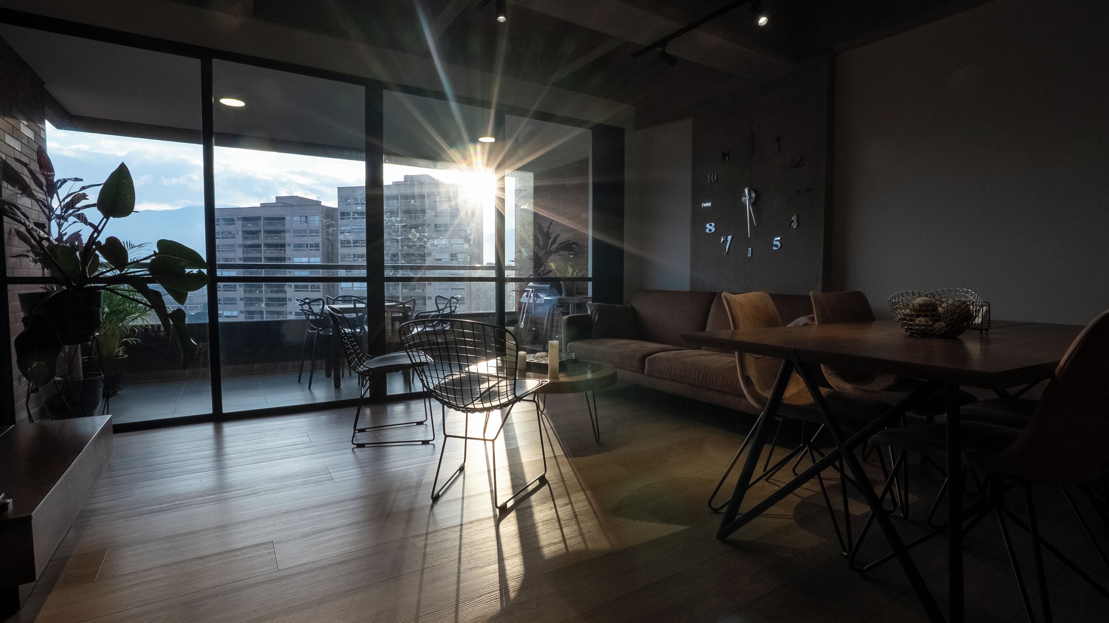 Een modern interieur met een eethoek, een bank en een groot raam met uitzicht over de stad.