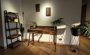 Une pièce avec un bureau en bois, une plante, une échelle et des œuvres d’art accrochées au mur.