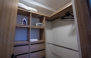 Un vestidor con estantes de madera, una barra para colgar y una toalla doblada en el estante inferior.