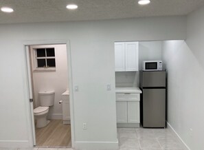 A compact kitchen with white cabinets, a microwave, and a refrigerator. - Cozy 1-bedroom studio in delightful Miami with AC comfort (Miami)
