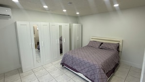 Ein Schlafzimmer mit einem Bett, einem Kleiderschrank und einer Decke mit Einbautenleuchten.
