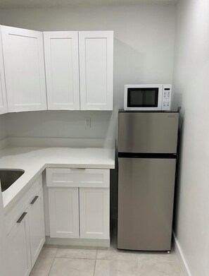 A kitchen with white cabinets, a stainless steel refrigerator, and a microwave. - Cozy 1-bedroom studio in delightful Miami with AC comfort (Miami)