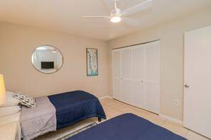 A bedroom with two beds, a ceiling fan, a mirror, a map, and a wardrobe. - Ocean Village Club G11, Ground Floor 2/2 Condo (St. Augustine)