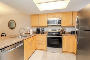 A modern kitchen with wooden cabinets, stainless steel appliances, a dishwasher, and a granite countertop. - Ocean Village Club G11, Ground Floor 2/2 Condo (St. Augustine)