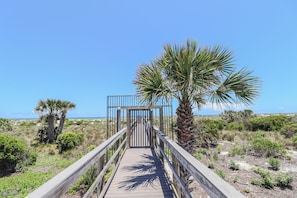 A wooden boardwalk leading to a gate, surrounded by vegetation and a clear sky. - Ocean Village Club G11, Ground Floor 2/2 Condo (St. Augustine)