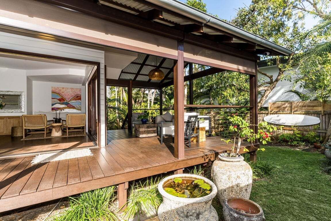 A wooden deck with outdoor furniture, a covered seating area, and a garden with potted plants.