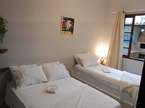 A hotel room with two beds, a wall-mounted artwork, and a window with curtains.